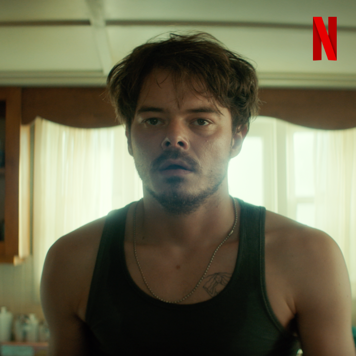 A Netflix promotional image shows a man with messy hair and stubble, wearing a tank top and silver chain, with a serious gaze directed at the camera, while the Netflix logo appears in the top right corner. The image's intense stare serves as a visual cue reminding viewers to take a break from scrolling and hydrate, reinforcing the post's message about self-care.