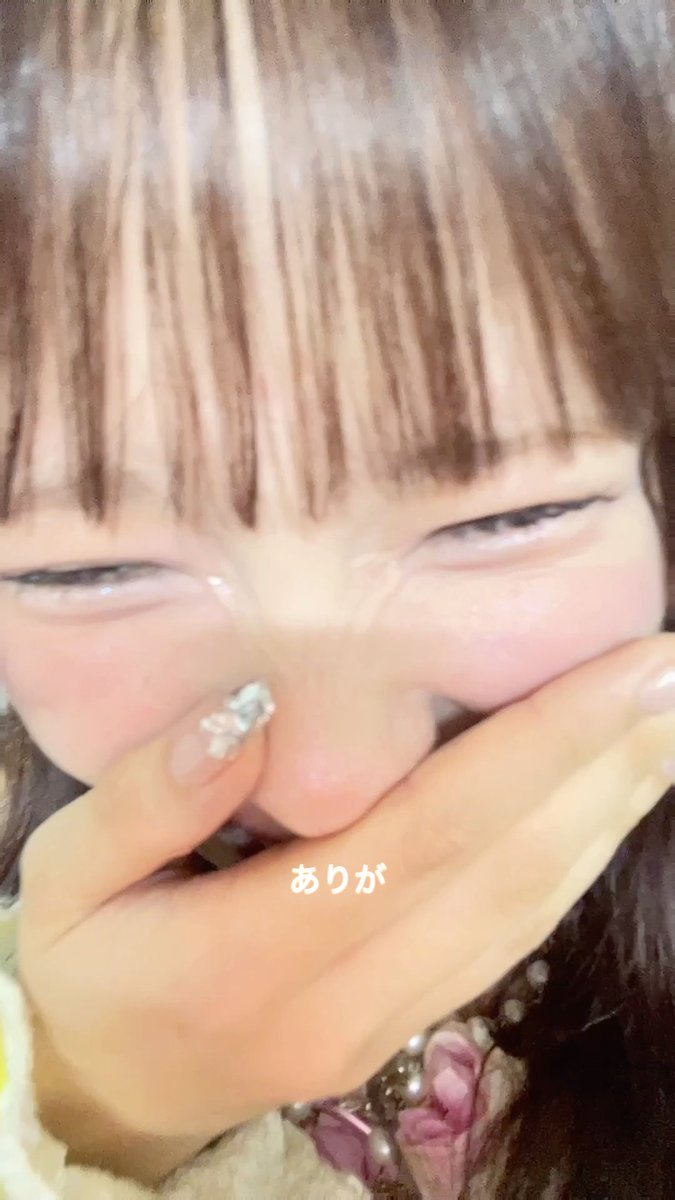 A close-up of a person with brown bangs and pink-tinted glasses pressing their hands to their face, with the Japanese text 'ありが' (arig) visible on screen.