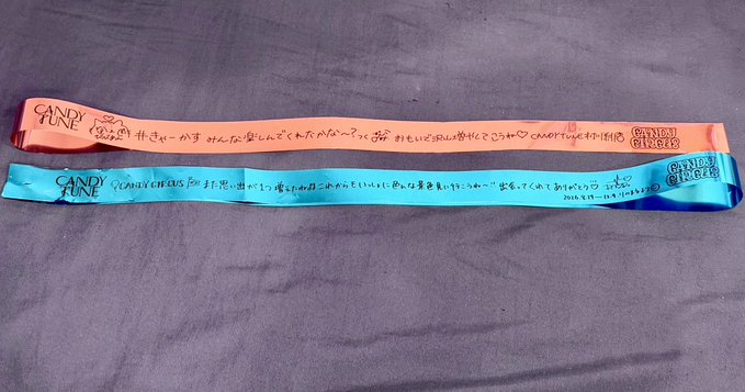 Two fabric wristbands (one peach/pink, one teal) labeled 'CANDY TUNE' with Japanese messages written in marker and the 'CANDY TUNE' logo printed on them.