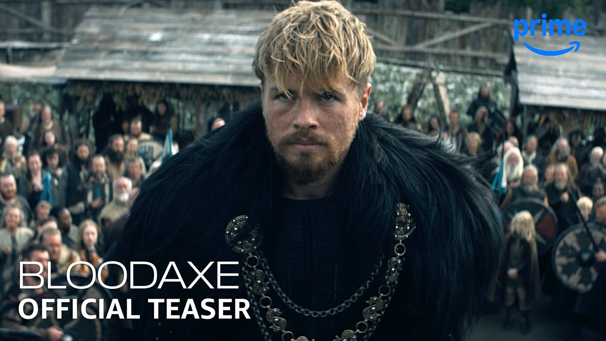 A blonde, bearded Viking warrior wearing a fur cloak and ornate metal chain stands sternly in the foreground, with a crowd of Norse warriors assembled behind him beneath wooden structures. The image is labeled "BLOODAXE OFFICIAL TEASER" and features the Prime Video logo, promoting the upcoming Viking series premiering January 20.