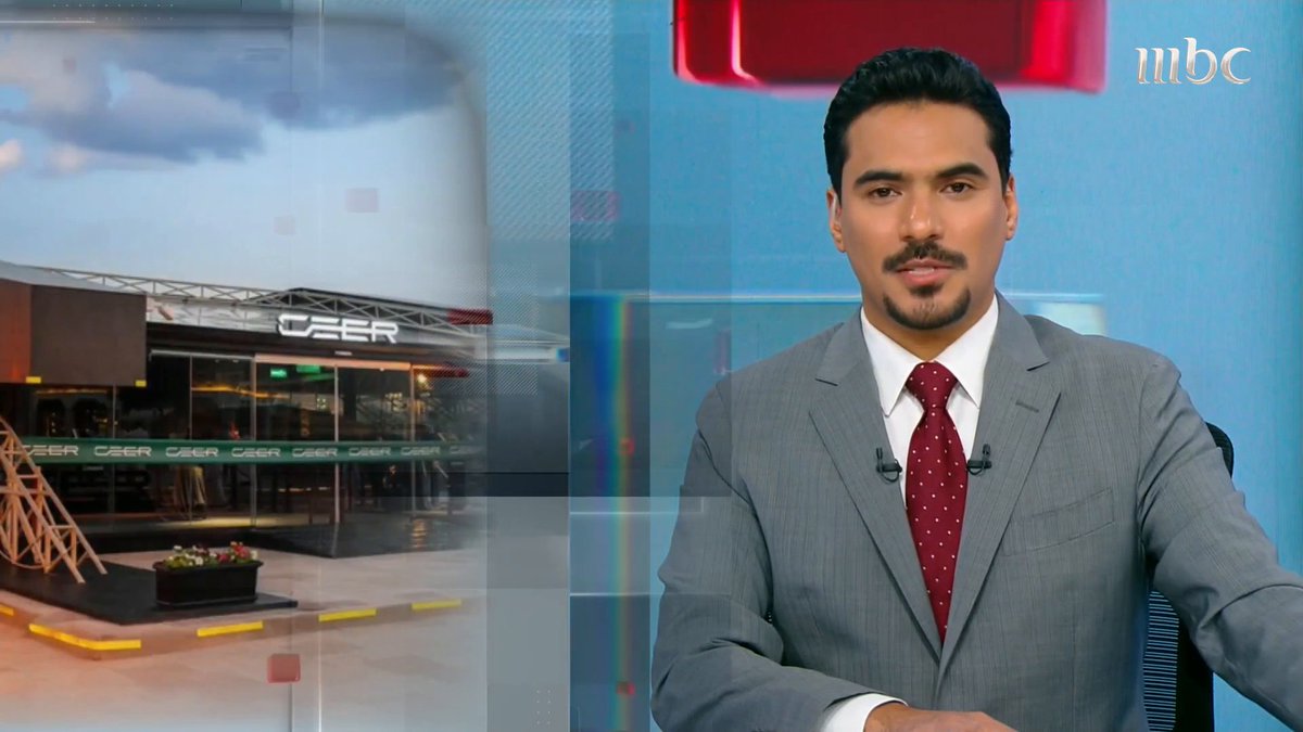 A male news anchor in a grey suit and red tie presenting on the MBC news channel, with a background image showing the CEER car brand showroom.