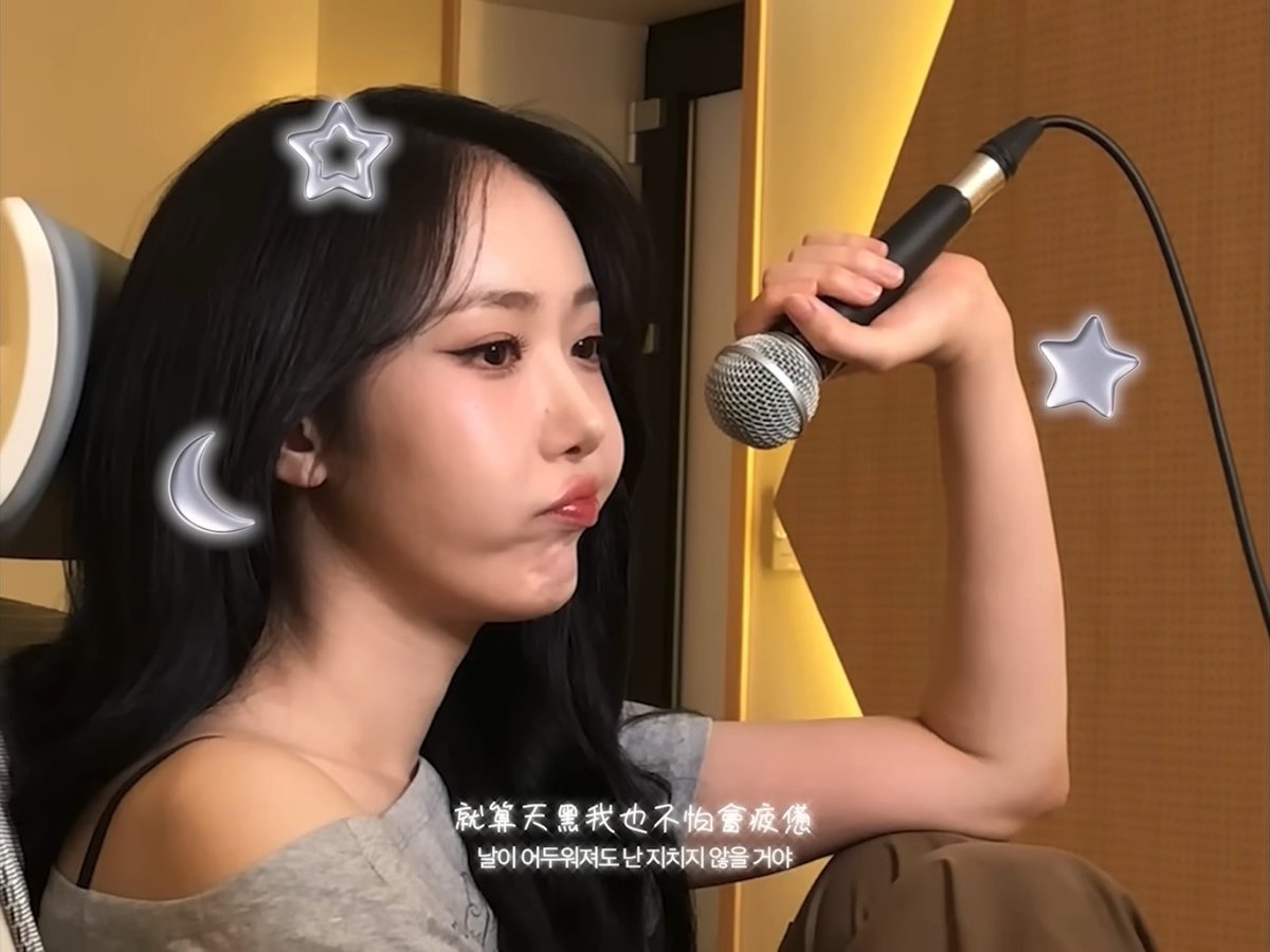 A woman with long dark hair sings into a microphone, with Chinese and Korean subtitles reading '就算天黑我也不怕會疲憊' and '날이 어두워져도 난 지치지 않을 거야'.