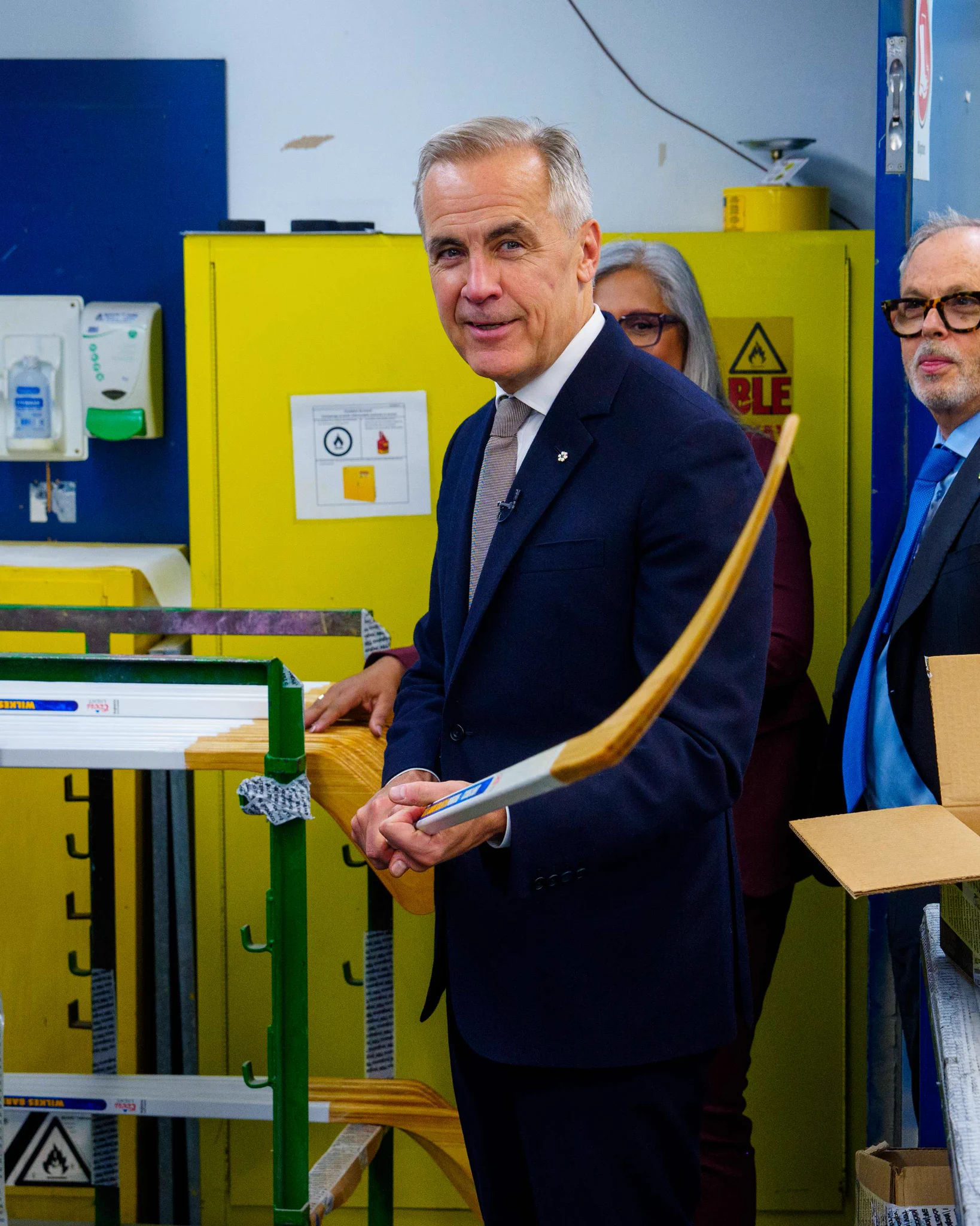 Prime Minister Mark Carney is holding a hockey stick. 