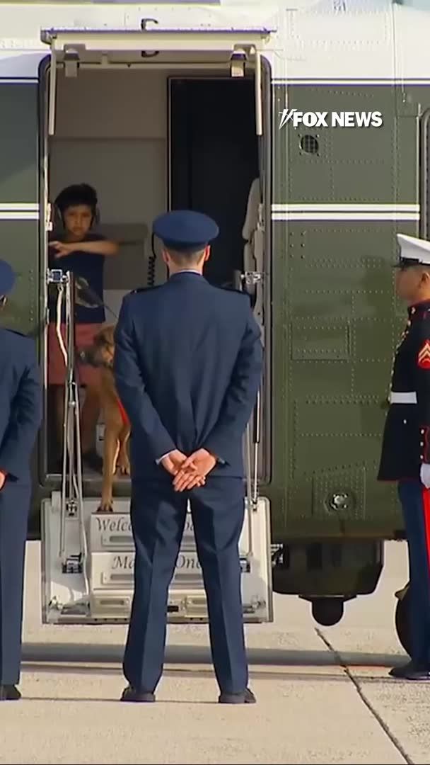 A screenshot from FOX NEWS shows a military scene with a uniformed officer standing at the base of an aircraft (likely Marine One), while children and a dog are visible inside the helicopter doorway.