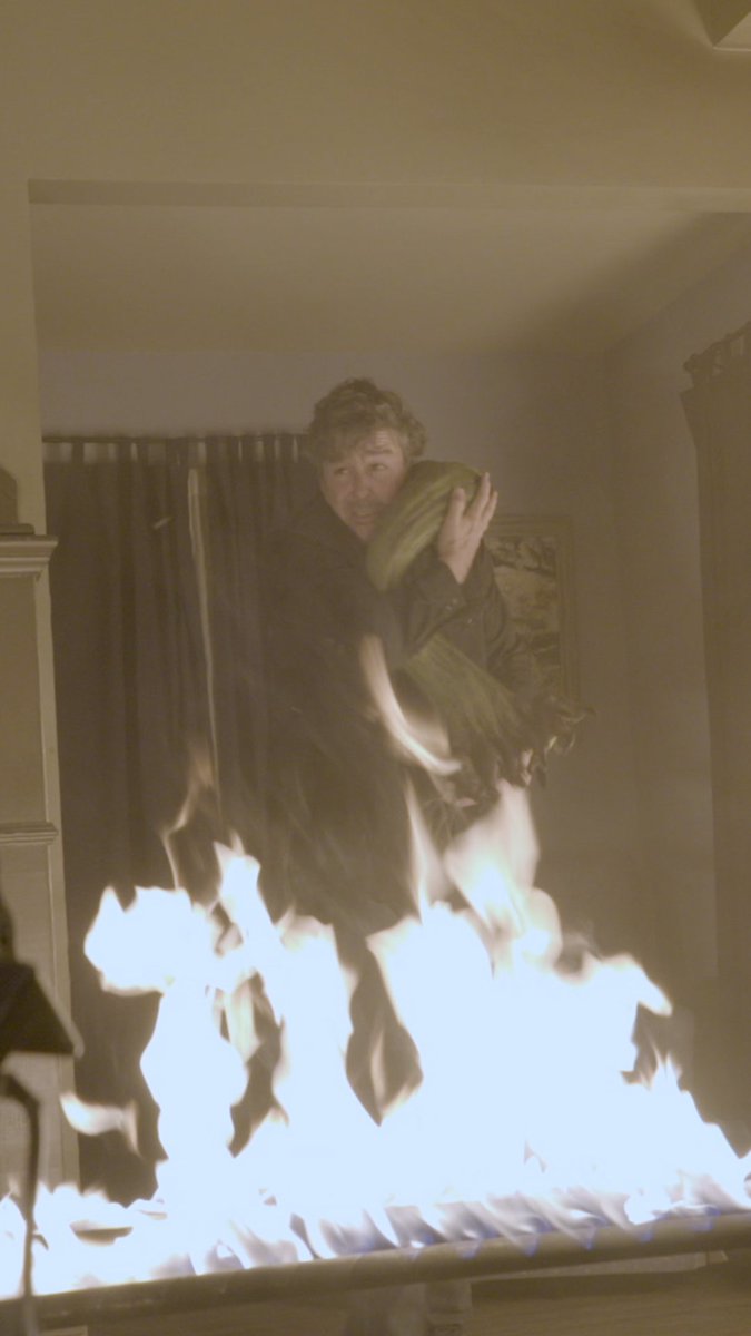 This appears to be a scene from the show "Earl" on Amazon, showing the character Earl sitting in an angel's arms amidst flames, matching the post's description of "Earl sits in the arms of an angel."