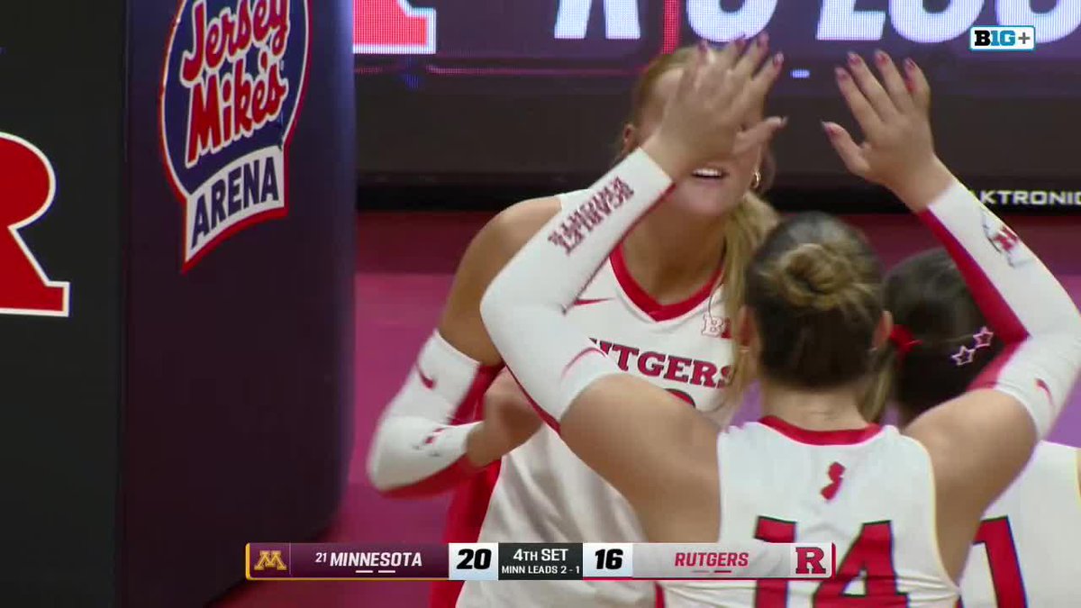 Rutgers volleyball players celebrating during a match against Minnesota at Jersey Mike's Arena, with the scoreboard showing Minnesota leading 20-16 in the 4th set.