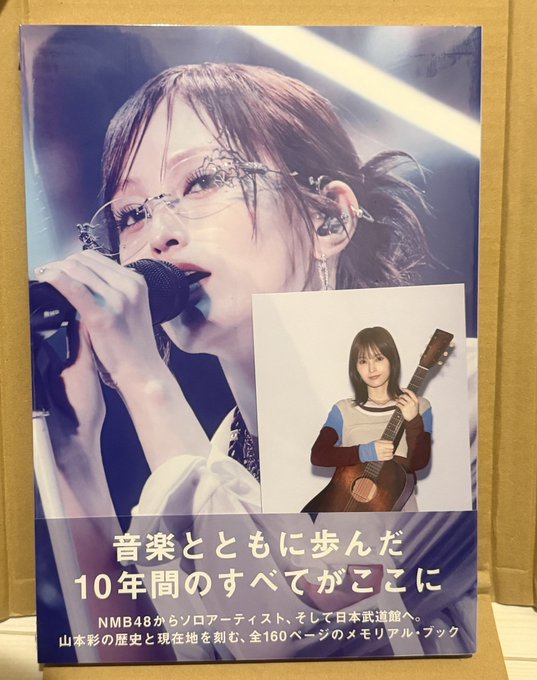 A memorial book for former NMB48 solo artist Yamamoto Sayaka, titled '音楽とともに歩んだ10年間のすべてがここに' (Everything from 10 years of walking with music is here), featuring her performing on stage and holding a guitar.
