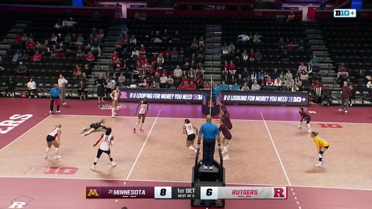 A women's college volleyball match between Minnesota and Rutgers, with the scoreboard showing Minnesota 8, Rutgers 6 in the 1st set, as players compete on the court.