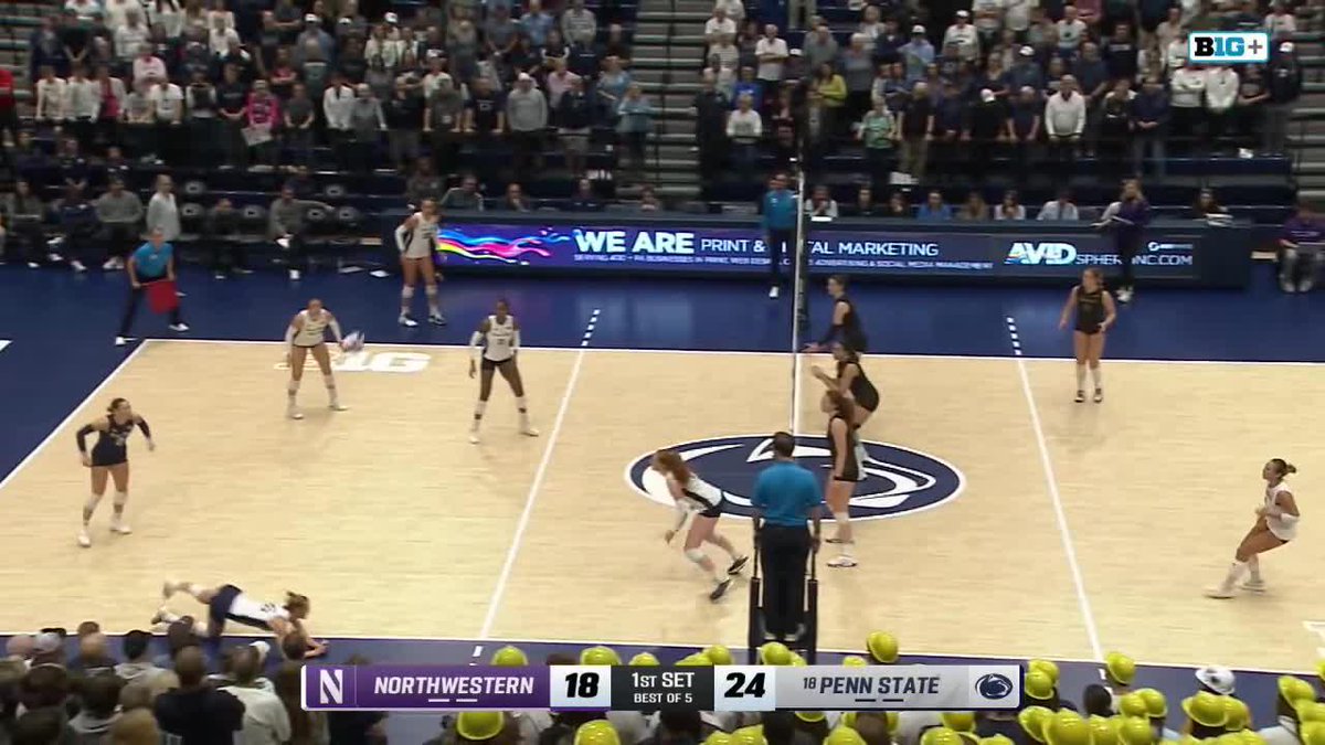 A Big Ten volleyball match between Northwestern and Penn State, with the scoreboard showing Penn State leading 24-18 in the first set, as a player dives for the ball near the sideline.
