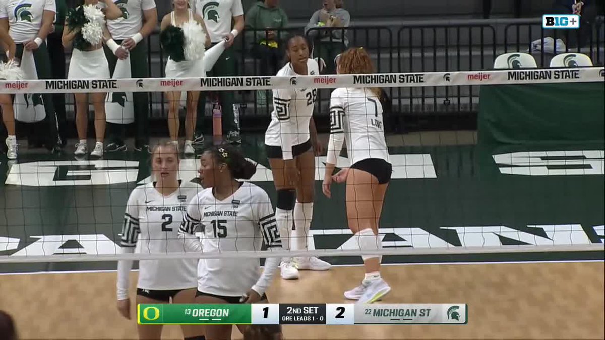 A screenshot from a Big Ten volleyball match between Oregon and Michigan State, with Michigan State players near the net and a scoreboard showing Oregon trailing 1-2 in the 2nd set.