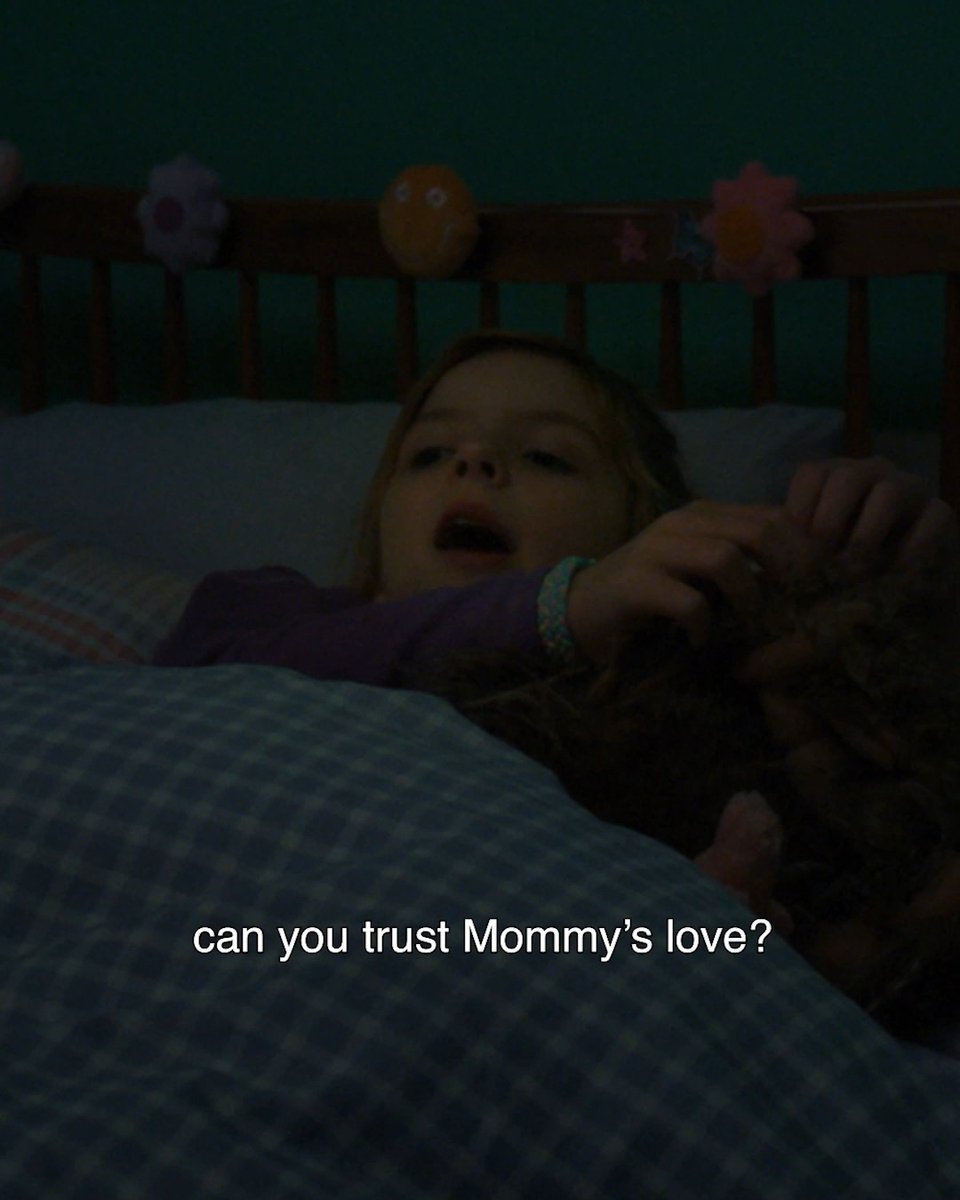 A young girl lies in bed in a dark room, with the text 'can you trust Mommy's love?' overlaid on the image.