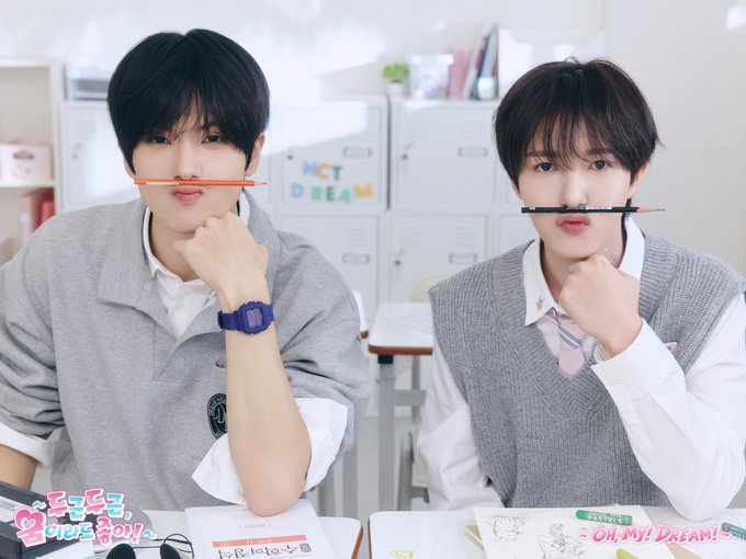 Photo of two young men in school uniforms sitting at a desk with pencils balanced on their upper lips, with Korean text '도티즌!' and 'OH, MY! DREAM!' visible at the bottom.