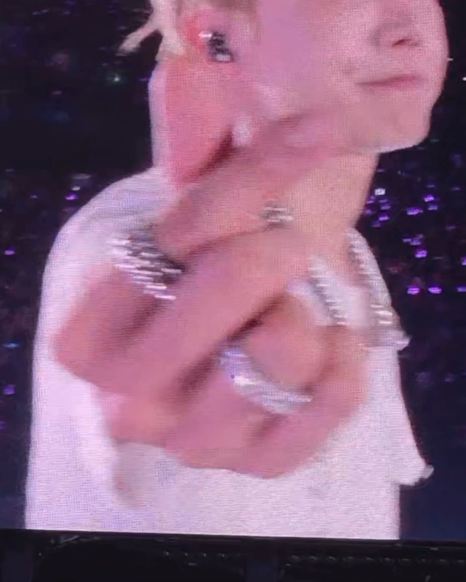 A blurry photograph of a performer with blonde hair wearing a sparkly outfit on stage with a purple sequined background.