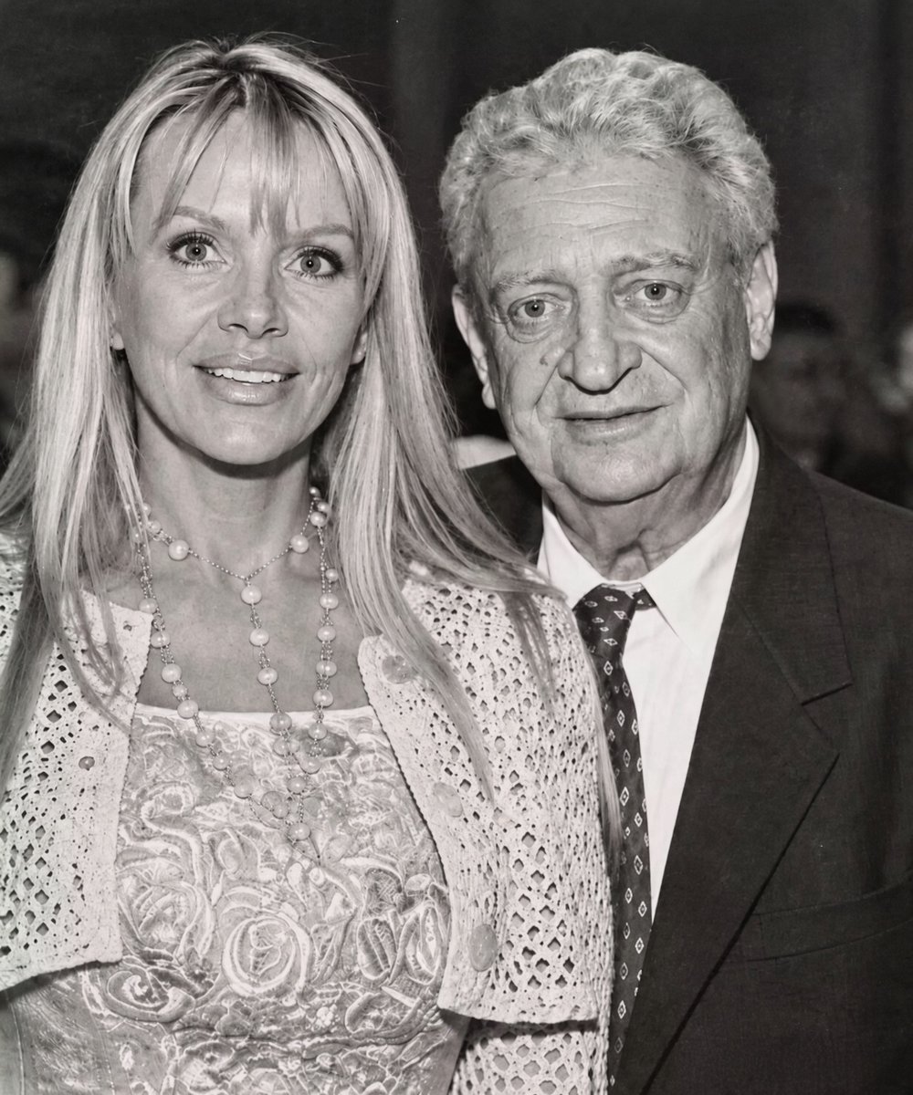 TrumpGirlLove's tweet photo. Rodney Dangerfield spent decades telling America that he got “no respect.” At 72, after a lifetime of turning rejection, disappointment, and failed relationships into comedy, he married Joan Child, the Santa Monica florist who had spent ten years seeing the gentle man behind the famous red tie. 

Their story began in 1983. Rodney walked into her flower shop and opened with a line so unusual it sounded like one of his own jokes. Joan recognized him immediately. 

She had watched him on television as a teenager, and now the comedian she remembered from “The Tonight Show” was standing right in front of her. Rodney asked what kind of drugs she liked. 

Joan, raised in a conservative Utah Mormon family, innocently replied, “Antibiotics, I guess.” Rodney was fascinated. He kept returning to the shop, often while she arranged flowers, until those visits became something they both looked forward to. 

Years later, Joan remembered that first moment with deep affection. To her, it felt like love at first sight. She saw a fascinating man with unforgettable blue eyes and a warmth that made her smile. Rodney was already a famous comedian, but their relationship moved slowly. 

They dated on and off for nearly ten years. He was about three decades older, lived an unusual comedian’s lifestyle, and carried the history of a difficult first marriage. But Joan saw something others missed. 

She waited for his phone calls. She looked forward to his visits. She loved the private humor that existed when no audience was around. The world knew the man who joked about being unwanted. Joan knew the man who wanted to be understood. She later described him as the funniest person she had ever known, but also as intelligent, caring, and deeply tender. 

That difference mattered. Because at home, Rodney did not have to perform rejection. On December 26, 1993, their long courtship suddenly became a marriage. Rodney and Joan went to Las Vegas, found a wedding chapel, and said their vows. He was 72 years old. 

The comedian who had spent decades turning loneliness and marriage troubles into jokes had finally entered a different chapter. Even after marriage, Rodney never stopped writing comedy. Joan became his favorite audience. 

He tested jokes on her, teased about married life, and made her laugh. She understood something important. Humor was not just his career. It was the way he survived pain, depression, aging, and memories from a childhood where affection was often hard to find. 

Their life together was unconventional. Rodney kept comedian hours, sometimes staying awake until the early morning. Joan managed much of their daily life and stayed beside him as his health declined. 

When he underwent brain surgery in 2003, she never left his side. She even joked that she sometimes needed an older husband because keeping up with Rodney was exhausting. Then came 2004. Rodney faced serious heart problems and underwent valve replacement surgery. 

Complications followed, including a stroke, infections, and other medical issues. He slipped into a coma. Joan stayed close. The florist who once watched him walk into her shop was now waiting for any sign that he was still there. 

Eventually, Rodney opened his eyes. Joan remembered the moment. He kissed her, squeezed her hand, and smiled at his doctors. Rodney Dangerfield died on October 5, 2004, at 82. 

He left behind decades of laughter, nearly eleven years of marriage, and a love that lasted far beyond the jokes. The man who spent his life asking for respect finally found someone who gave it to him every day. ❤️
