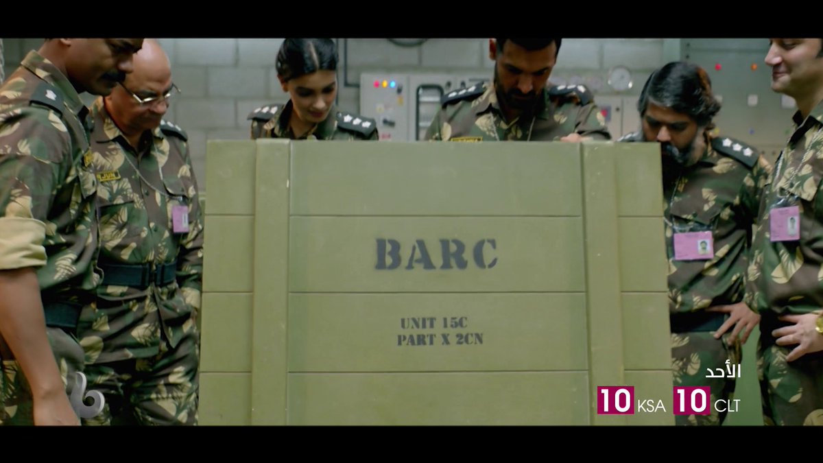 A group of military officers in camouflage uniforms gather around a green crate labeled 'BARC UNIT 15C PART X 2CN', with a '10 KSA 10 CLT' watermark in the corner, suggesting a scene from a film or show.