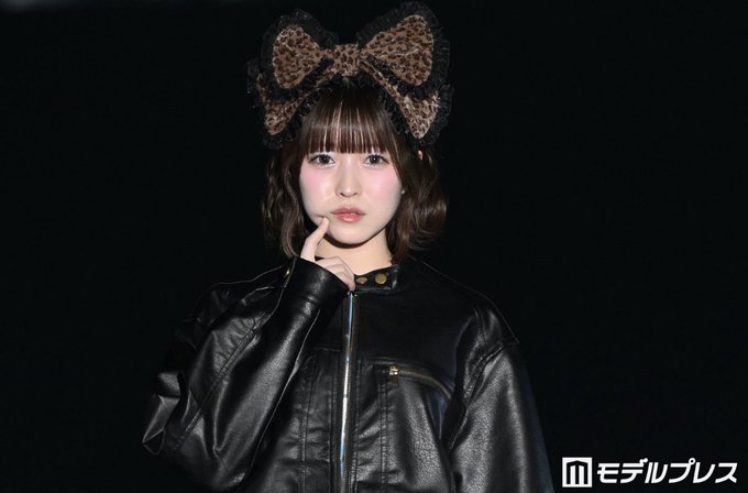 A portrait photo of a young woman wearing a black leather jacket and a leopard print bow headband, with 'モデルプレス' watermark in the corner.