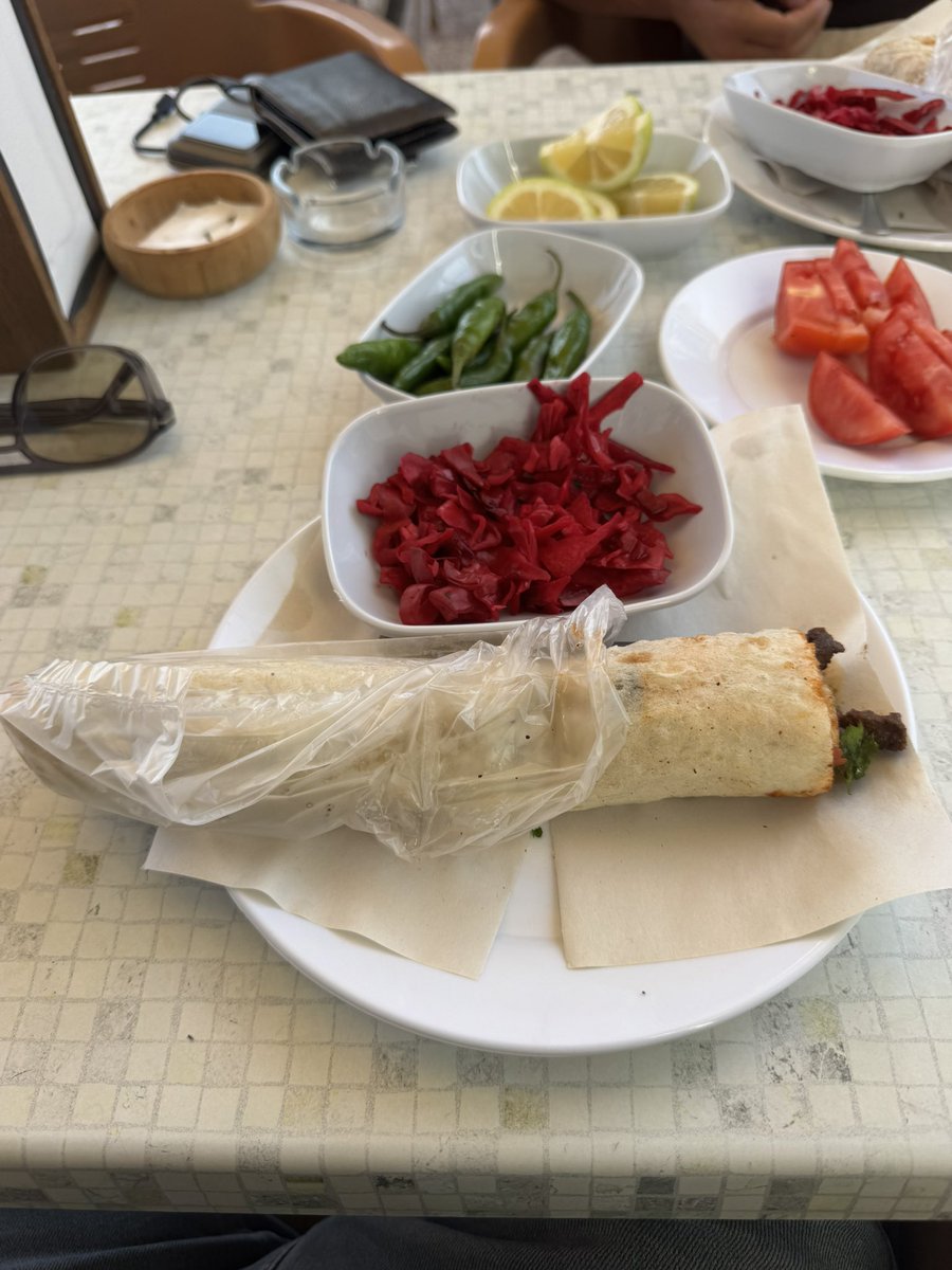 insaatuzmani's tweet photo. Mersin’de 34 yıldır aynı küçücük dükkanda tantuni yapan bir karı koca düşünün. Ne reklamları var ne gösterişli bir mekanları. Sadece işlerini yapıyorlar ama öyle bir tantuni yapıyorlar ki bana göre Mersin’de ellerine su dökecek başka bir yer yok!

Daha önce de paylaşmıştım burayı. Bugün yine uğradım, Sami amcamızla biraz daha sohbet ettik. Ben burayı 15-20 yıllık bir işletme sanıyordum. Meğer tam 34 yıldır aynı yerde, aynı işi yapıyorlarmış. Gerçekten şaşırdım. Eşiyle beraber kafa kafaya vermişler, 34 yıldır bu küçücük dükkanda alın teri döküyorlar. Resmen yaşayan bir çınar burası.

Mersin’e taşınalı 11 yıl oldu. Biz burayı yaklaşık 5 yıl önce tesadüfen keşfettik. Battı çıktı yapıldığı için dükkan biraz geride kalmış. Öyle yoldan geçerken görüp durabileceğiniz bir yer değil. Daha çok bilenlerin gittiği bir mekan.

Şimdi size çok net söylüyorum. Bir gram abartmıyorum, reklam değil, tamamen kendi tavsiyem. Burası benim için MERSİN’İN EN İYİ TANTUNİCİSİ. Mersin’de bir sürü yerde tantuni yedim. Bugün yine uğradım, iki tane açık ekmek biftek tantuni yedim. Arkadaş, böyle bir lezzet olamaz!

Mersin’de yaşayıp buradan tantuni yemeyen, samimi söylüyorum, ben tantuni yedim demesin. O kadar iddialıyım.

Dükkan eski, salaş ama tertemiz. Sami amcamız ve eşi sürekli ellerini yıkıyor, işlerini büyük bir özenle yapıyorlar. Sami amcamızın o naifliği, güler yüzlülüğü, işine duyduğu sevgi sanki yaptığı tantuniye geçmiş. Öyle bir lezzet ki tadı damağımda kalıyor, başka yerde tantuni yiyesim gelmiyor. Ne gösteriş var ne süs. 34 yıldır aynı yerde, aynı lezzeti yaşatan iki güzel insan var.

Şehir dışından Mersin’e gelecekseniz en iyi tantuniyi nerede yerim diye araştırmanıza gerek yok. Gidin burada yiyin, sonra bana teşekkür edersiniz.

Buranın adı Düzgün Tantuni. Abidin Tantuni’yi biraz geçiyorsunuz, denize doğru, petrolün ve Yeni Parti İl Başkanlığının olduğu yere gelmeden küçük, salaş bir dükkan.

Bir de sizden özellikle ricam var. Mersin’de yaşayanlar, Mersin’e gelmeyi düşünenler, tantuni sevenler… Lütfen bu paylaşımı birbirinize gönderin. Sami amcamıza ve eşine destek olalım. 34 yıldır aynı yerde emek veren, artık tarihi bir değer haline gelmiş bir esnafımızdan bahsediyoruz. Dükkanı biraz geride kaldığı için herkesin gözüne çarpmıyor. Böyle insanların, böyle emektar esnafların kıymetini bilmemiz lazım.

34 yıldır aynı yerde tantuni yapan Sami amcamızın ve eşinin ellerinden öpüyorum. Hem emeklerine hem lezzetlerine saygı duydum.

Anlatılmaz, yaşanır. Lütfen gidin, deneyin, çevrenize tavsiye edin. Hem gerçek tantuniyi yiyin hem de 34 yıllık bu güzel emeğe sahip çıkın arkadaşlar. ❤️Mekanın ismini iletişim bilgilerini aşağıya bıraktım.