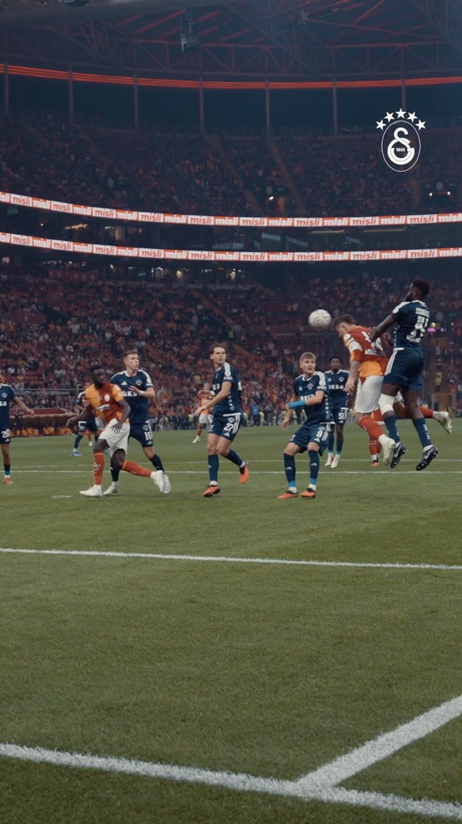 A soccer player leaps high to head the ball into the goal during a match at a packed stadium, with "misli" branding visible on the LED boards. The action captures the moment of the scoring header, aligning with the post celebrating the captain's opening goal from Batrakov's assist.