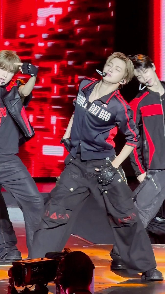 A performer in a black and red outfit with the text "ROMEO & JULIET" on his jersey strikes a dramatic stage pose with fellow dancers against a vivid red backdrop, perfectly matching the guilty, self-blaming sentiment of "It's all my fault."