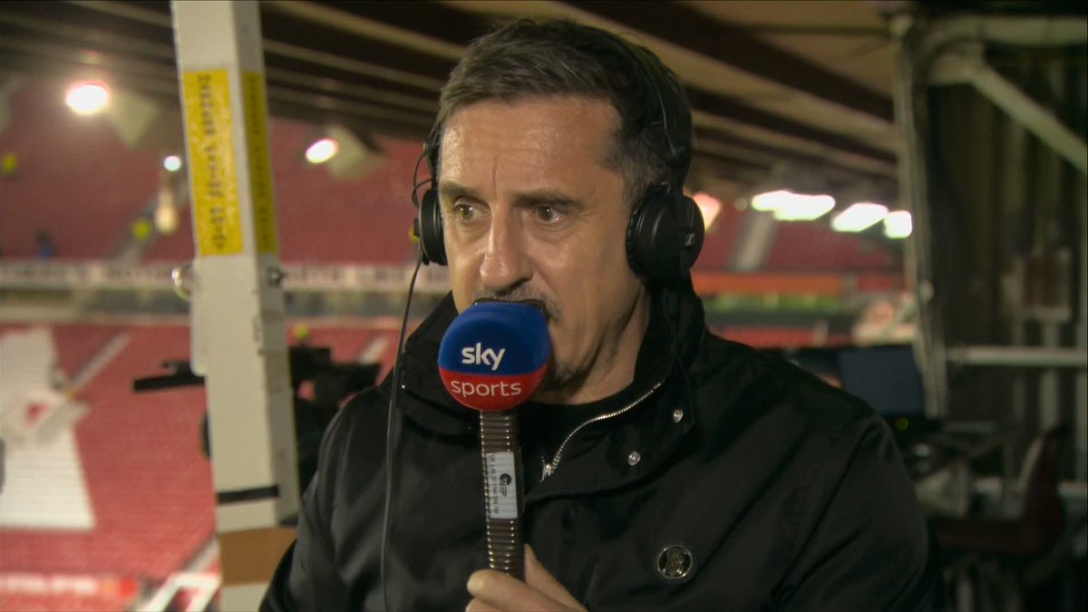 Former footballer and Sky Sports pundit Gary Neville is shown speaking into a "Sky Sports" branded microphone while wearing broadcast headphones, with a football stadium visible behind him. The image aligns with the post's commentary on his criticism of Manchester United's midfield pairing of Tielemans and Mainoo.