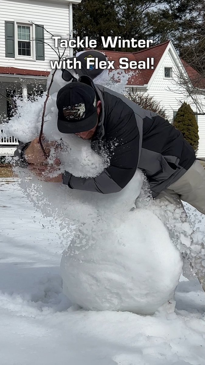 A man in a black jacket and cap wrestles with a giant snowman in a snowy yard in front of a white house, with the caption 'Tackle Winter with Flex Seal!'