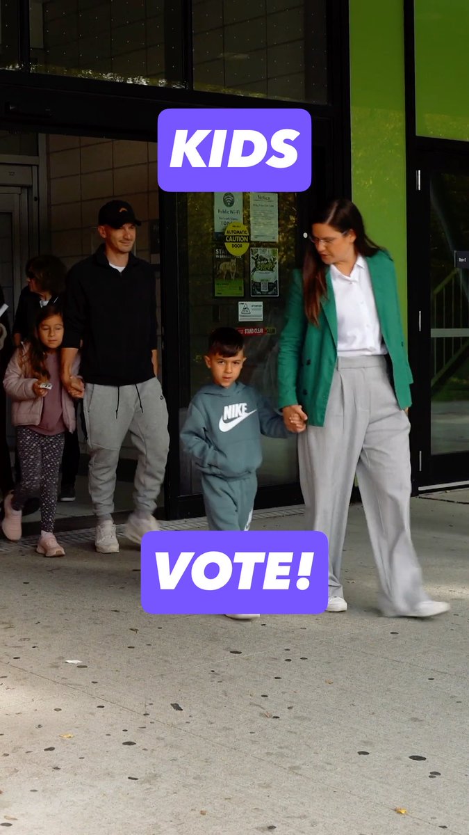 A family of four walks outside a building; the image features text overlays reading 'KIDS' and 'VOTE!' in purple boxes.
