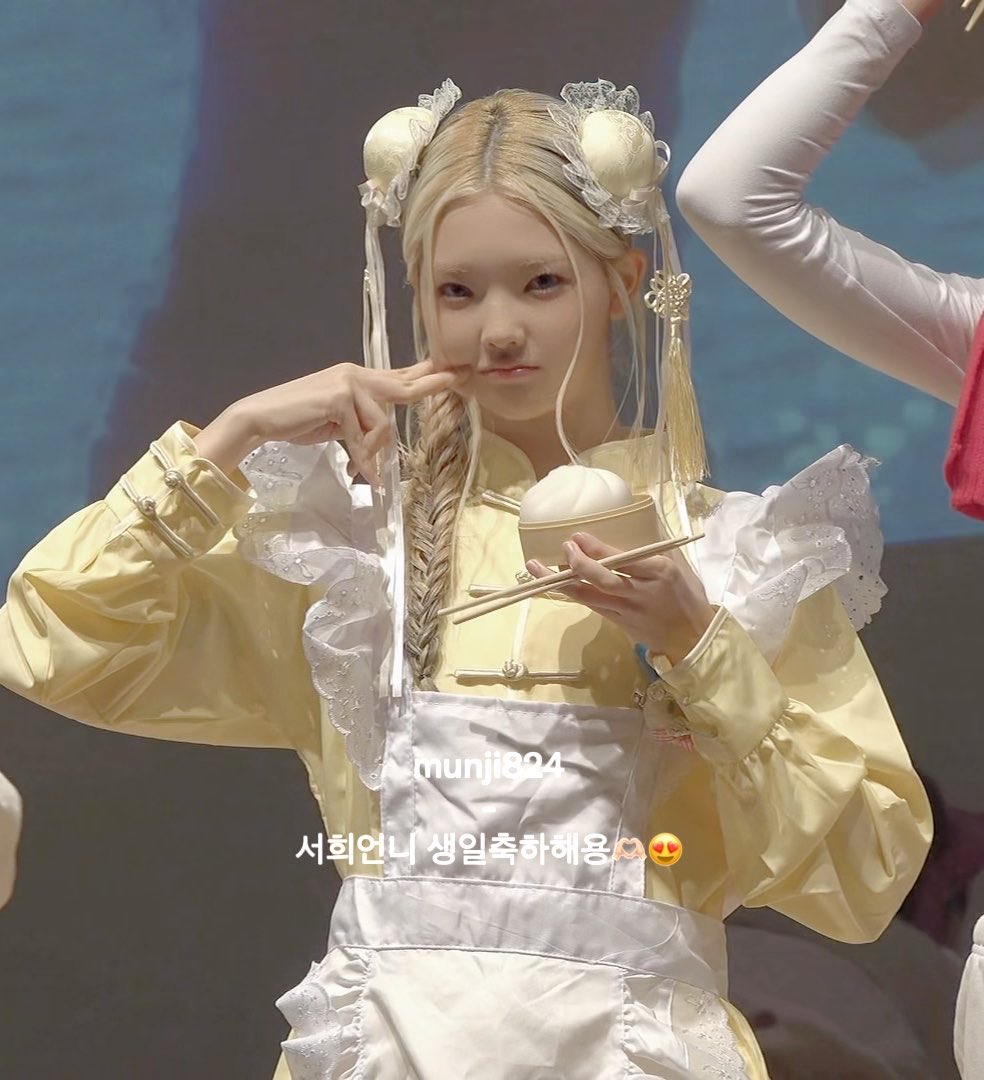 A blonde performer in a yellow Chinese-style costume holding a bao bun and chopsticks, with text reading 'munji824' and '서희언니 생일축하해용'.