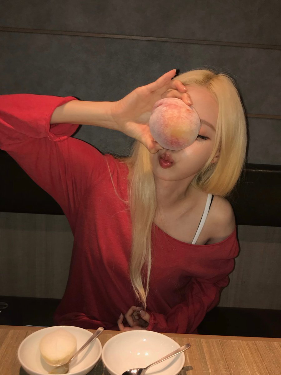 minwjong's tweet photo. peach &amp; coconut dreams  

fruit held like little secrets,  
soft pout under warm restaurant light —  
sweet playfulness in every glance 🍑✨  

where ordinary treats turn into pure magic. https://t.co/Z6ici8wGsH