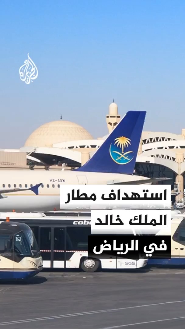 Saudi Arabia's flag adorns the tail of an aircraft parked at King Khalid International Airport in Riyadh, as Arabic text reports an attack on the facility causing injuries and temporary suspension of operations. The image, featuring a Cobalt-branded shuttle bus and the registration "HZ-ASW," aligns with the post's news of a strike on the Riyadh airport.