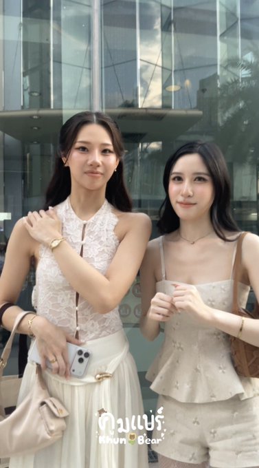 Two young women pose together in elegant white outfits, with text at the bottom reading "กินแบร์ Kinuni Bear."