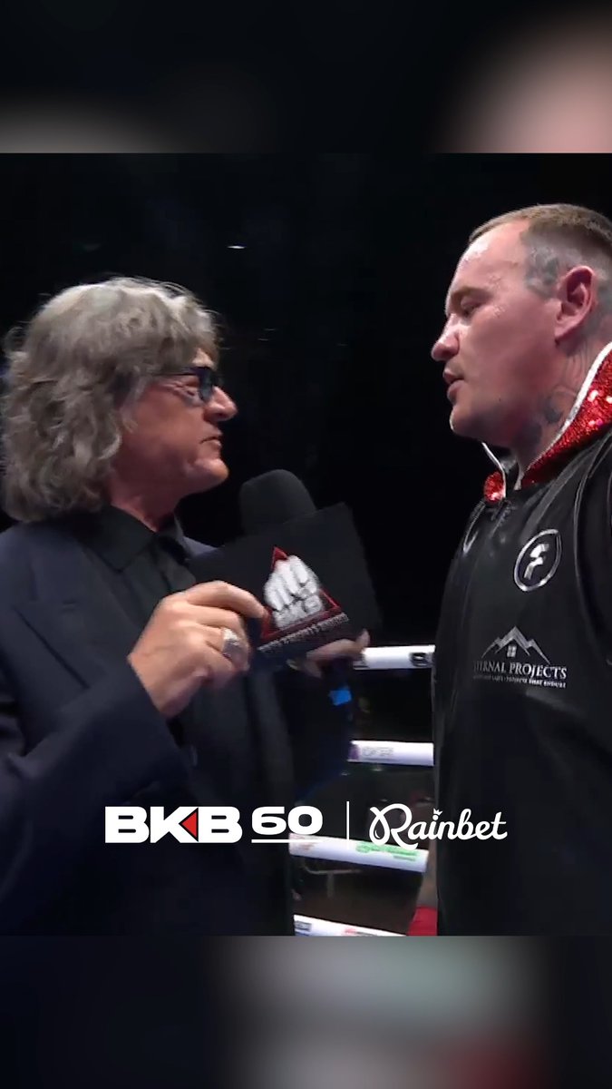 Two men face each other in what appears to be a pre-fight interview setting; the man on the right is heavily tattooed and wearing a black and red jacket, while the man on the left holds a microphone and a BKB-branded item. Text at the bottom reads "BKB 60 | Rainbet".
