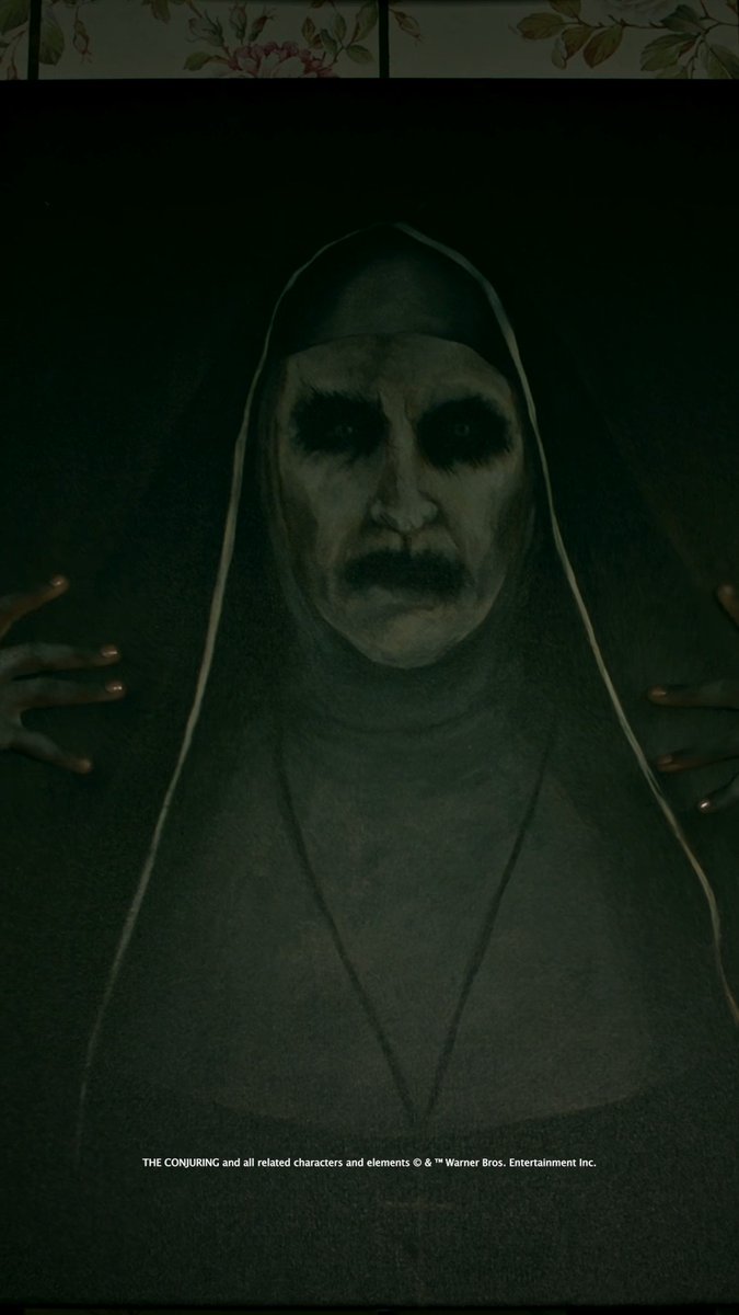 A dark, eerie promotional poster from "THE CONJURING" franchise featuring a demonic nun figure with a pale, sunken face and dark eyes emerging from shadows.