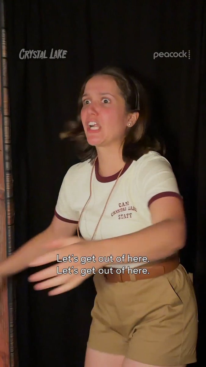 A frightened young woman wearing a Camp Crystal Lake Staff ringer t-shirt and tan shorts pleads to escape, with subtitles reading "Let's get out of here. Let's get out of here." The image promotes the Peacock series "Crystal Lake," whose logo appears in the top left corner.