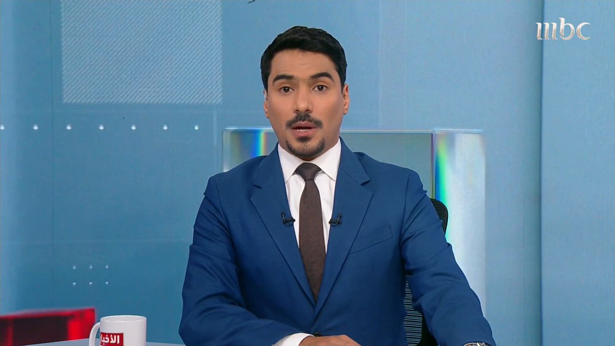 A male news anchor with a goatee, wearing a blue suit and brown tie, speaks on an MBC news broadcast set with the 'mbc' logo in the corner.