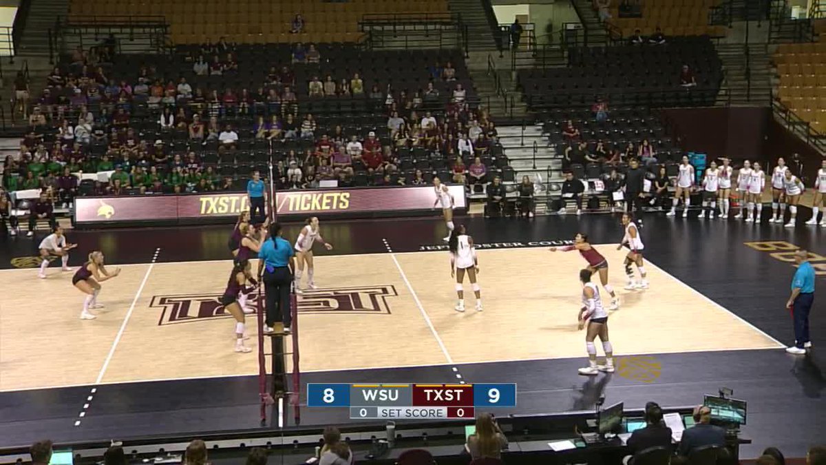 A women's volleyball match between WSU and TXST is in progress, with the scoreboard showing WSU trailing TXST 8-9 in the first set on a court marked with the TXST logo.