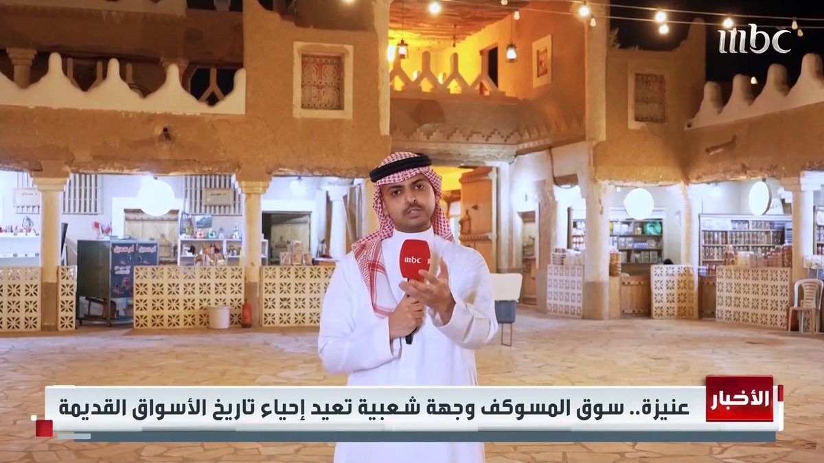 An MBC news broadcast showing a reporter in traditional Saudi attire (white thobe and red-checkered keffiyeh) standing in a traditional marketplace, with Arabic text reading 'عنيزة.. سوق المسوكف وجهة شعبية تعيد إحياء تاريخ الأسواق القديمة'.