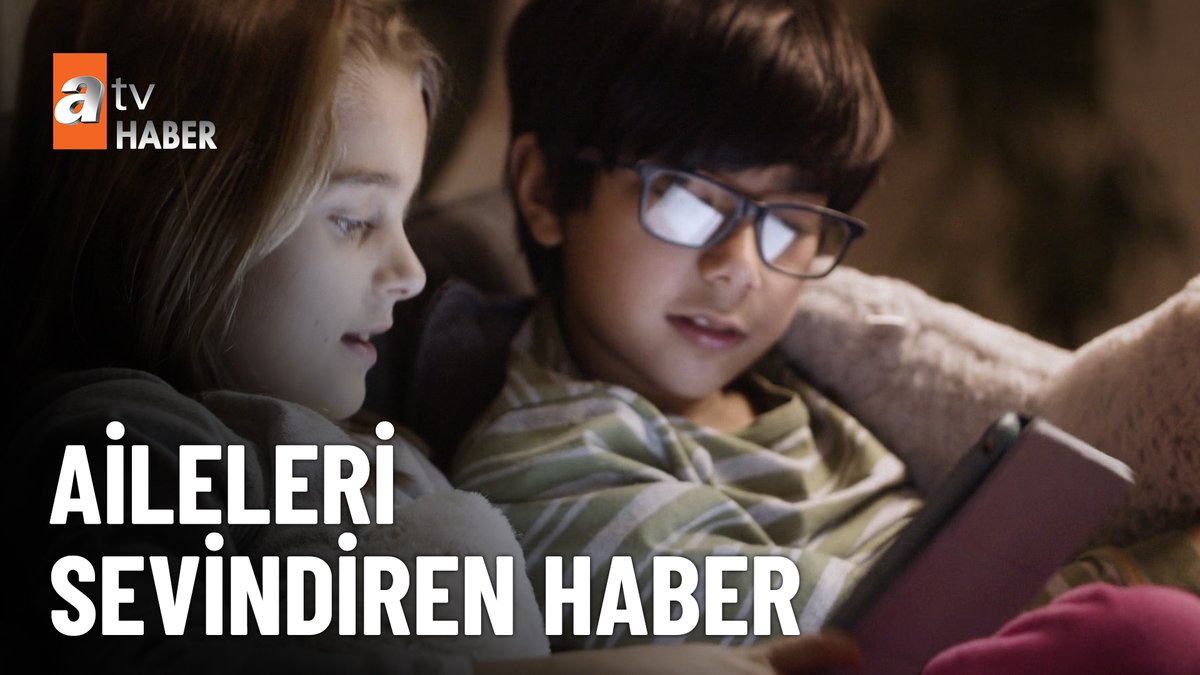 Two children, a boy wearing glasses and a girl, look intently at a tablet screen while lying down together. An "atv HABER" logo is visible in the top left, with Turkish text below reading "AİLELERİ SEVİNDİREN HABER".