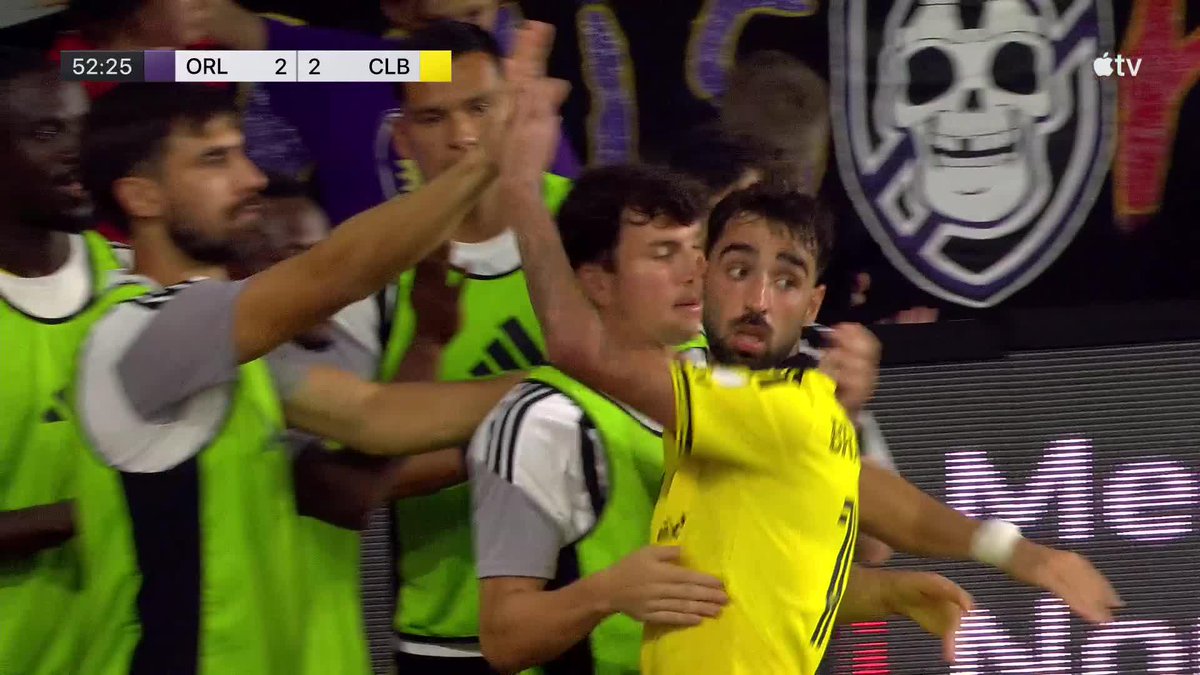 A broadcast screenshot shows soccer players in yellow and green training bibs celebrating on the sideline, with a scoreboard in the top-left reading '52:25 ORL 2 - 2 CLB' and an Apple TV logo in the top-right.