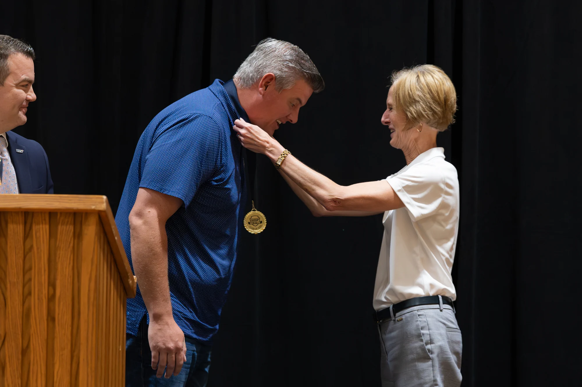 A woman places a Prairie Stars Hall of Fame medal around an inductee's neck during the ceremony.