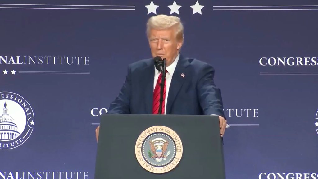 Donald Trump stands at a podium featuring the Seal of the President of the United States, delivering remarks at an event with a backdrop reading 'NATIONAL INSTITUTE' and 'CONGRESS' under five stars.