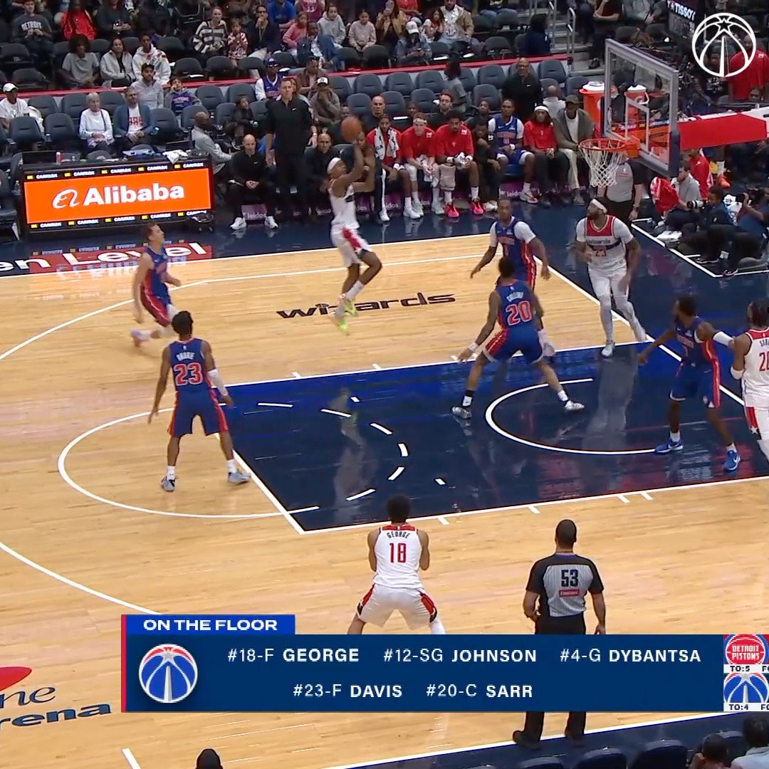 A Wizards player takes a jump shot over Pistons defenders during an NBA game at the Wizards' home arena, with an "Alibaba" ad visible on the scorer's table and a graphic showing Washington's "On the Floor" lineup: George, Johnson, Dybantsa, Davis, and Sarr. The "Good bucket Tre" caption suggests Tre Johnson (#12) likely hit the contested jumper shown.