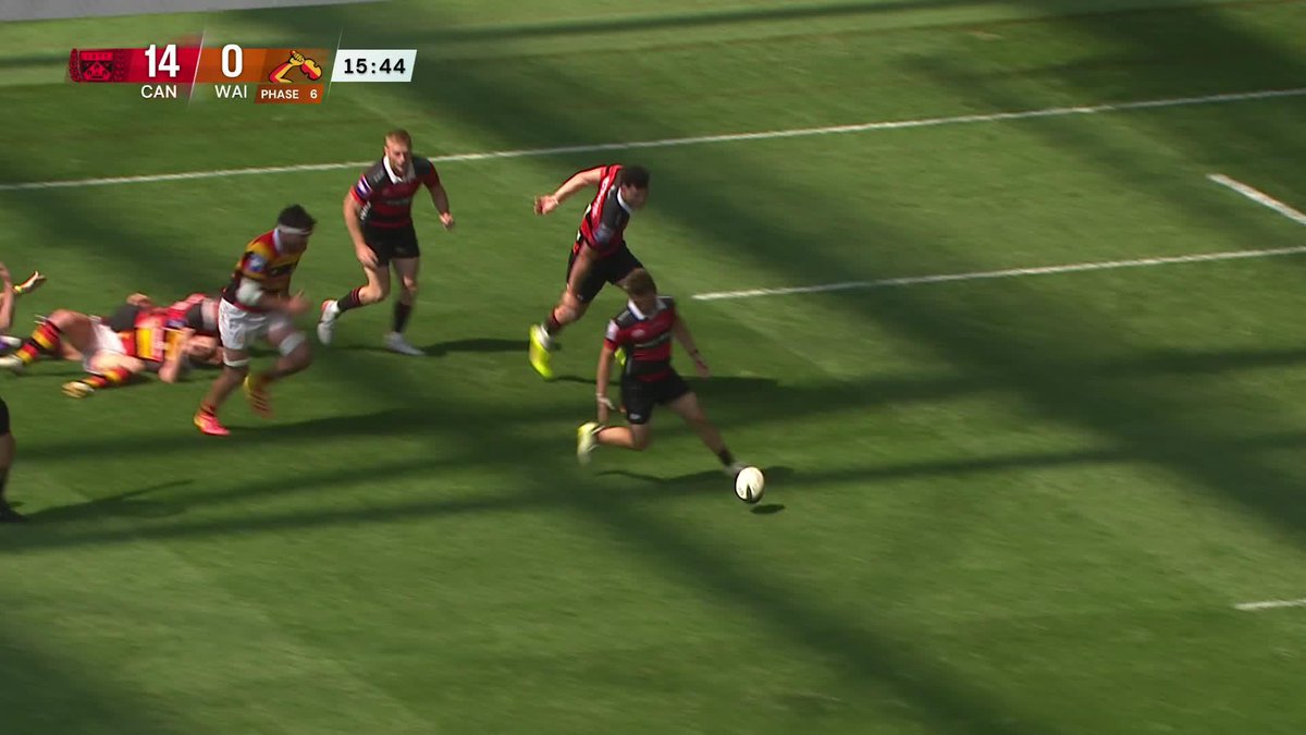 Rugby match screenshot with overlay text 'CAN 14 | 0 WAI, PHASE 6, 15:44', showing players in red/black and yellow/black uniforms competing for the ball on the field.