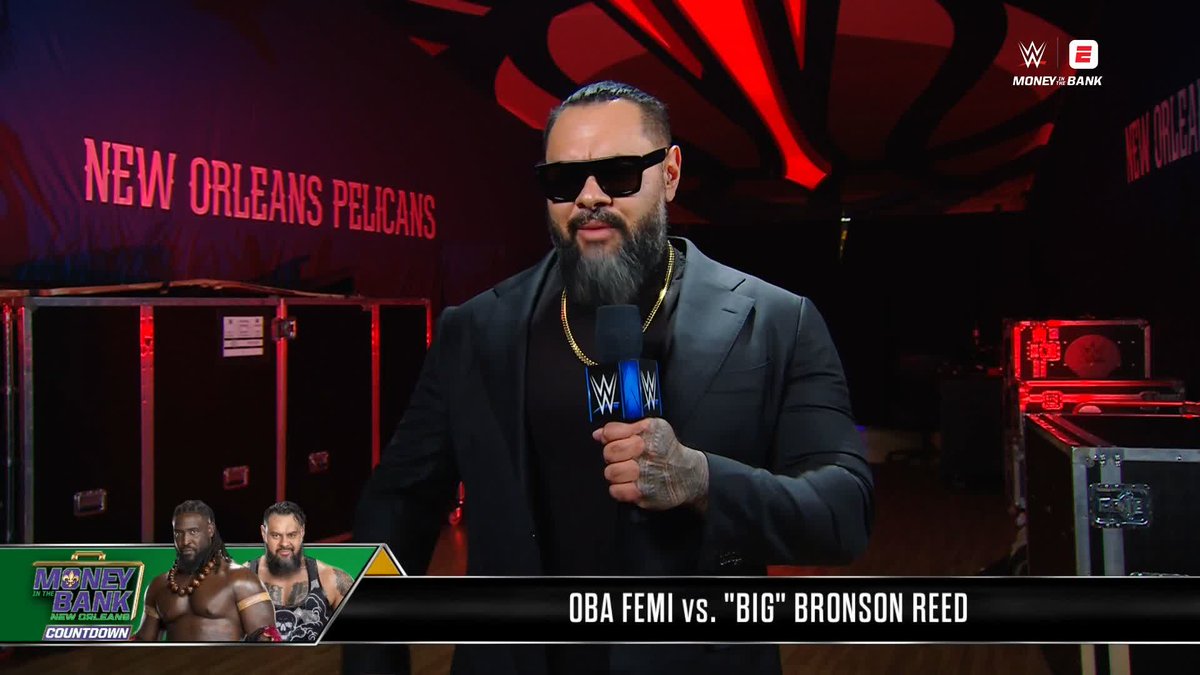 A WWE Money in the Bank "Countdown" segment features Oba Femi, wearing a black suit and sunglasses, holding a WWE-branded microphone during a backstage promo ahead of his match against "Big" Bronson Reed in New Orleans. The on-screen graphic highlights "OBA FEMI vs. 'BIG' BRONSON REED," with ESPN branding in the top right corner, tying into the post's promotion of the pre-show streaming on ESPN.