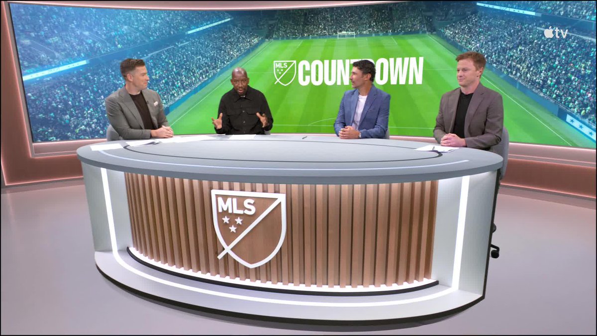 Four men sit at a desk with the MLS logo in a sports studio during an Apple TV "MLS Countdown" broadcast, with one guest in a black shirt gesturing as he speaks to the three co-hosts in suits. The caption aligns with the post as it appears to capture the moment MLS legend Michael Parkhurst joins the Columbus Crew vs. Atlanta United pregame show.
