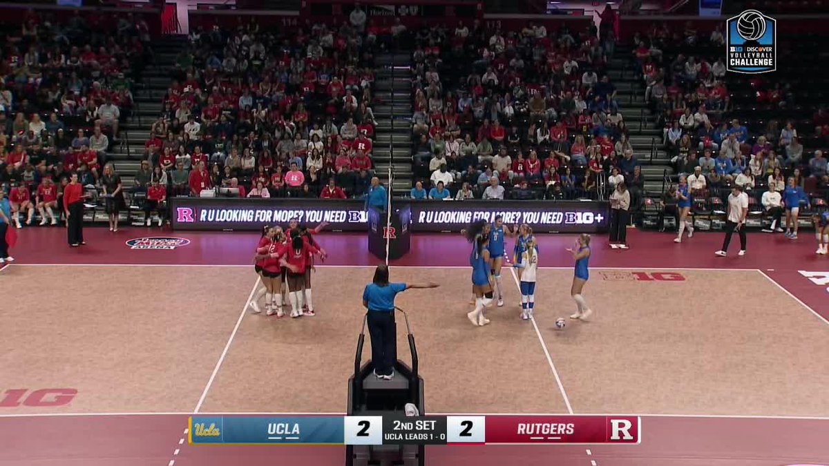 A volleyball match between UCLA and Rutgers during the 2nd set, tied 2-2, with players gathering on the court under B1G Discover Volleyball Challenge branding.