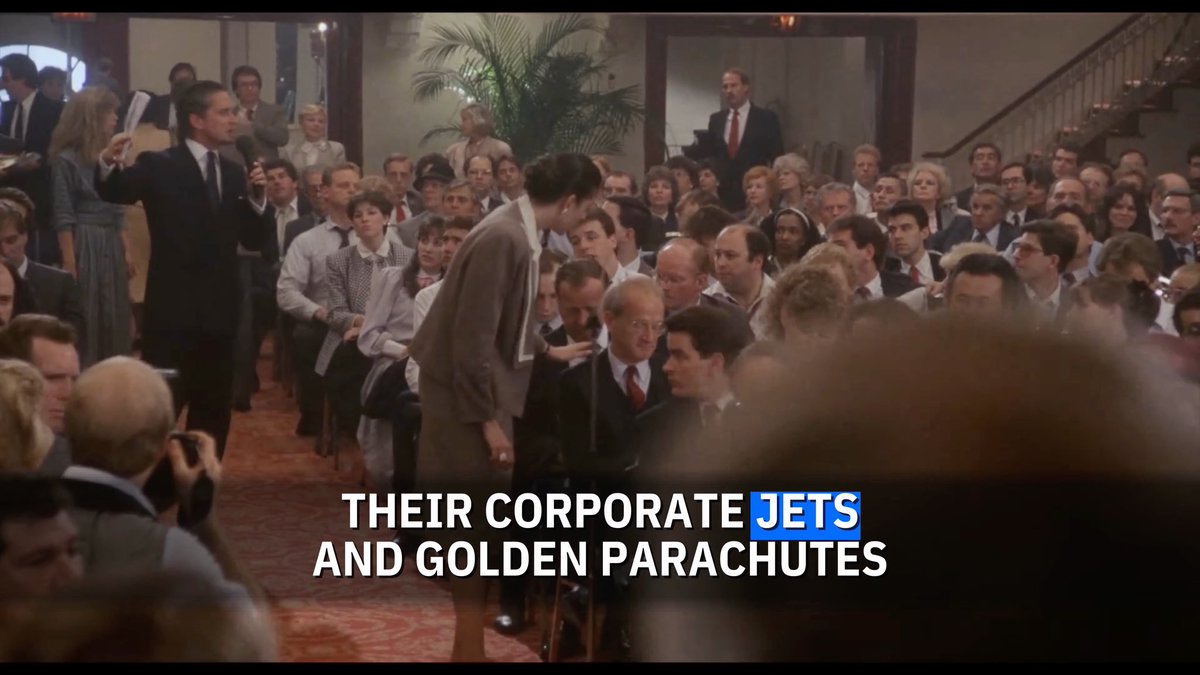 A crowd scene from the 1987 film "Wall Street" shows packed attendees at a stockholders meeting, with on-screen text reading "THEIR CORPORATE JETS AND GOLDEN PARACHUTES" — visually reinforcing Gordon Gekko's famous speech about corporate greed, executive excess, and the accountability shareholders bear when management fails.