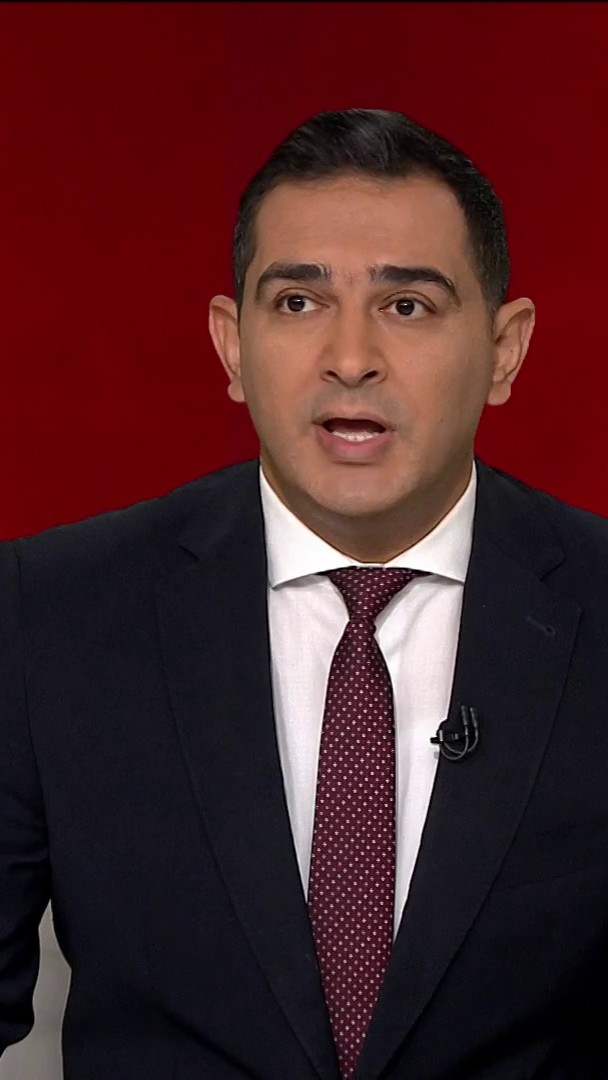 I'm not able to identify the specific person shown in the image. 

What I can describe: A man in a dark suit, white shirt, and patterned maroon tie is speaking, with a small lapel microphone visible. He appears to be in a formal interview or broadcast setting with a red background.

If you could confirm who this is, I'd be happy to help write a caption that connects the image to the accompanying statement about the attacks on Riyadh and condolences for the American victim.