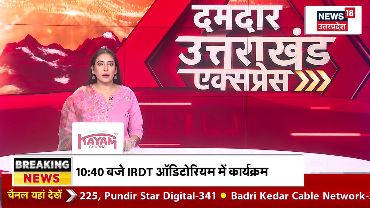 A female news anchor in a pink outfit presents on a red-themed set for News18 Uttar Pradesh, with a ticker reading "10:40 baje IRDT ऑडिटोरियम में कार्यक्रम" and text promoting a "Damdar Uttar Khand Express" show.