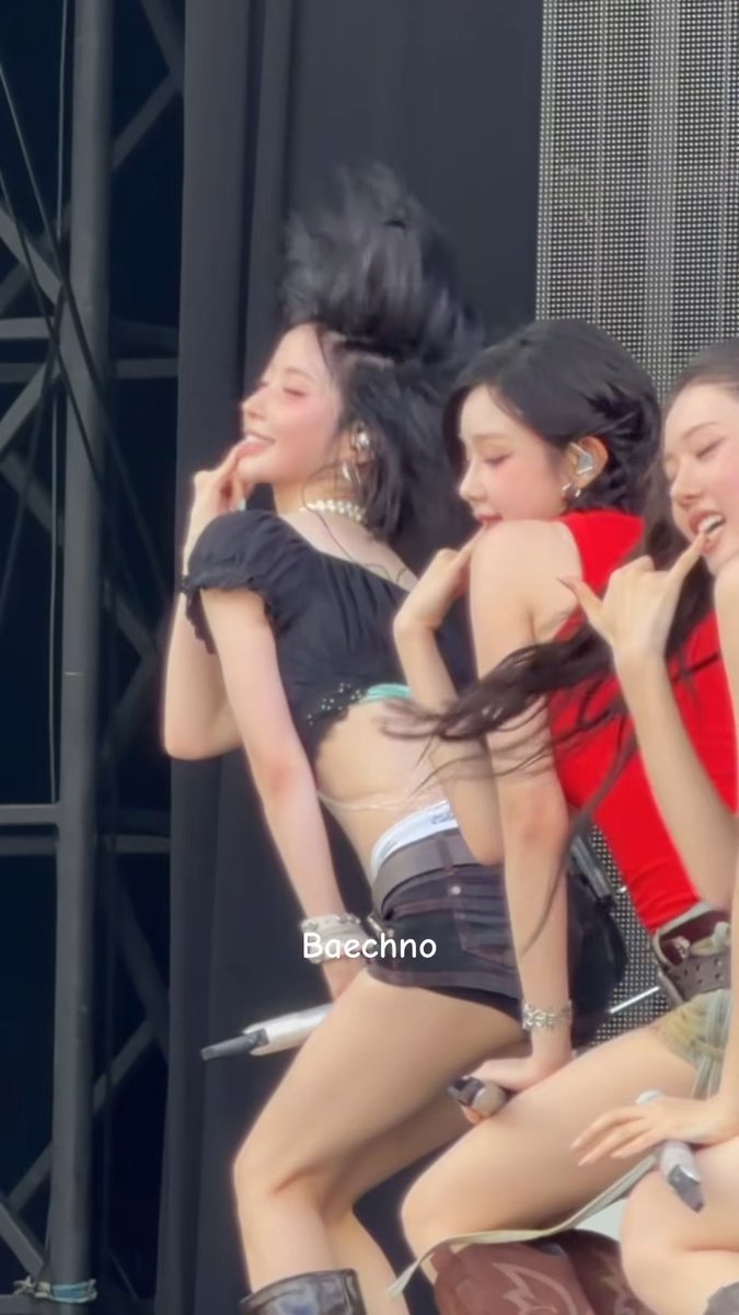A concert/festival photo showing female K-pop performers dancing on stage, with one wearing a black crop top and another in red, captured mid-performance with text overlay 'Baеchno' watermark.