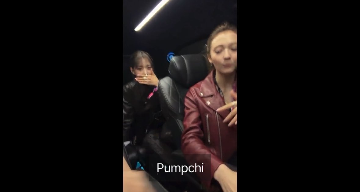 Two women sit in a dark vehicle; the woman on the left covers her mouth in surprise while the other in a red leather jacket speaks to the camera, with the text 'Pumpchi' displayed.